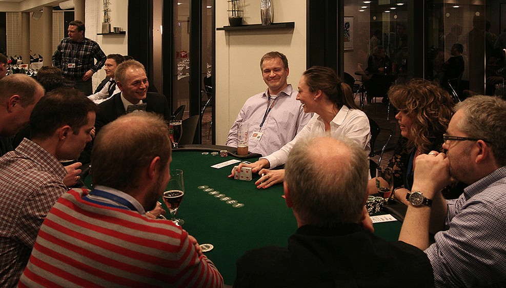 Gæster spiller poker og griner sammen ved bordet til poker event